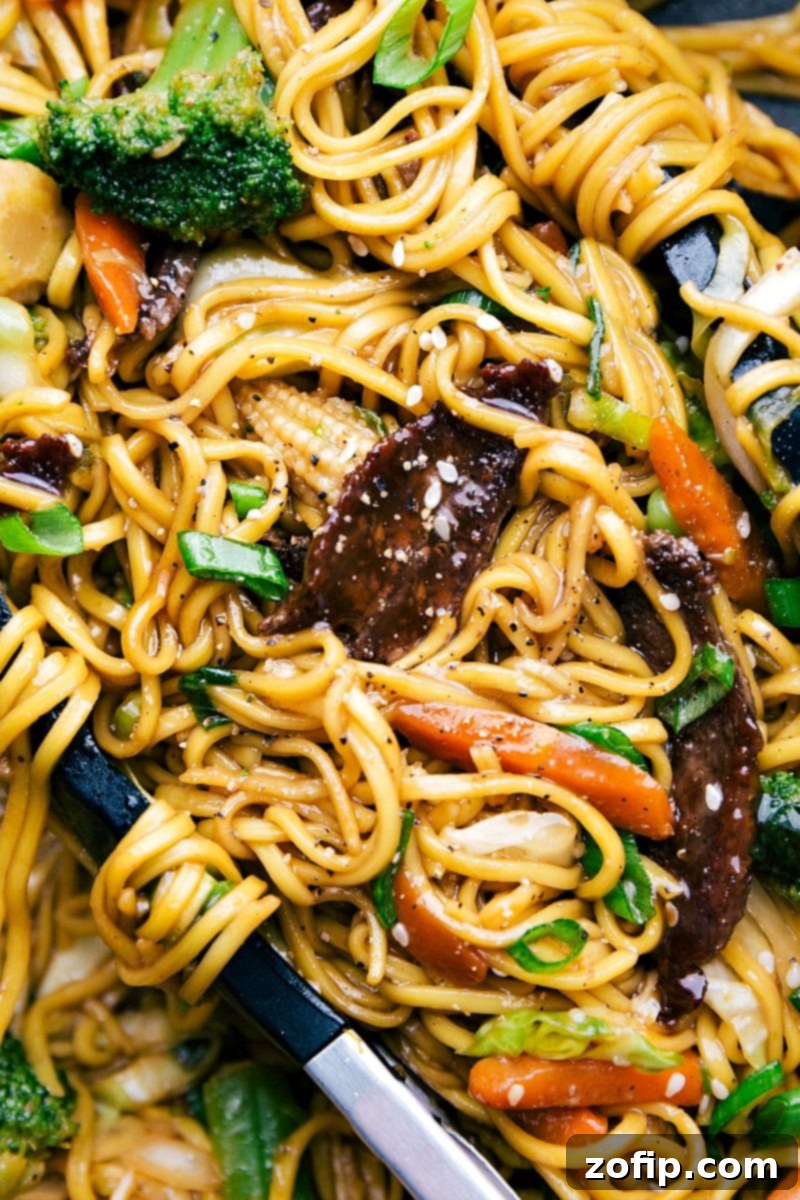 Finished Beef Chow Mein with tongs holding the noodles, showcasing its delicious appearance.