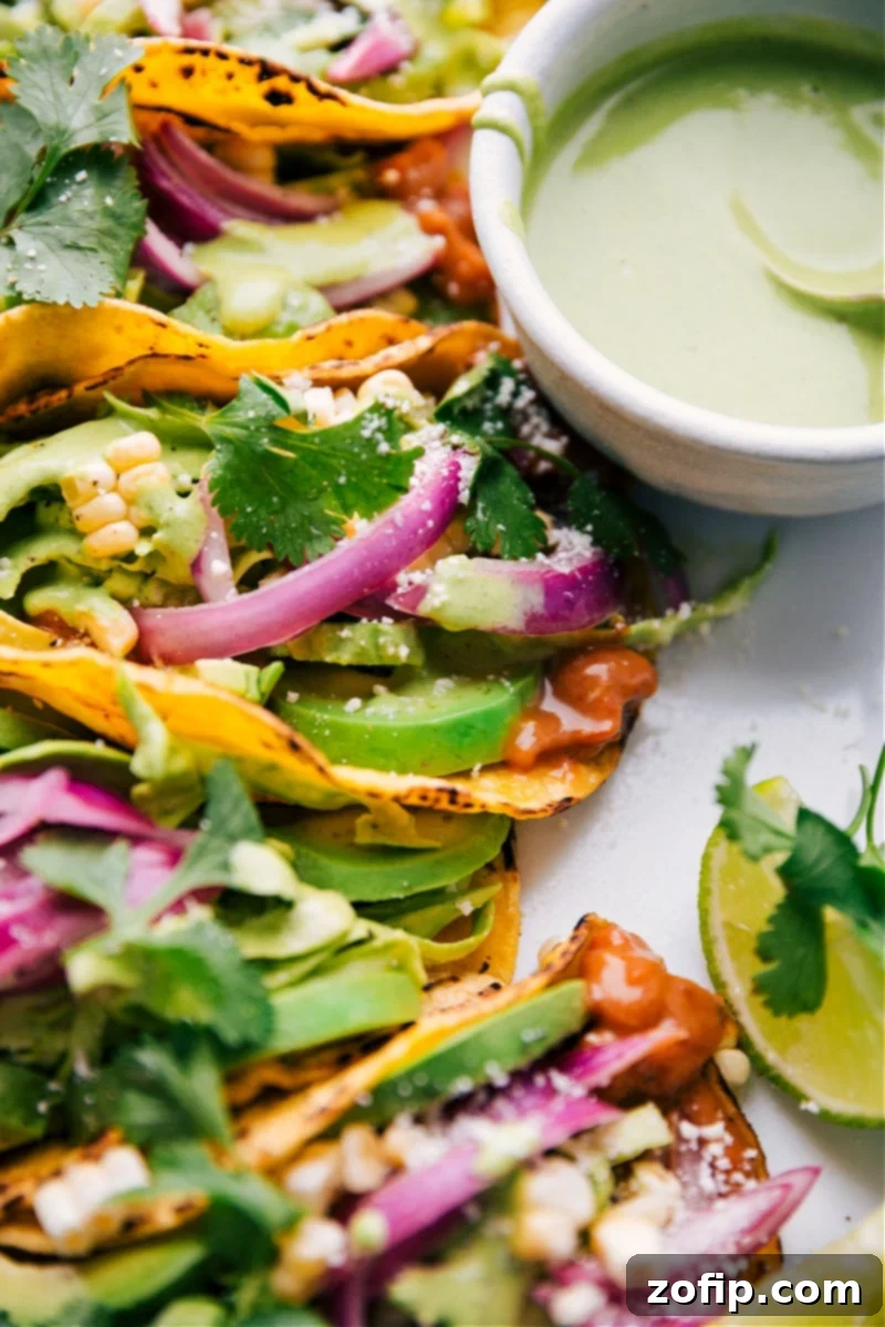 Delicious Pinto Bean Tacos: Light, Healthy, Fresh, and Crunchy. Featuring saucy pinto beans, cilantro-lime slaw, crisp corn, and tangy quick-pickled red onions. Overhead shot of two beautifully assembled Pinto Bean Tacos on a white plate, garnished with fresh cilantro and lime wedges, emphasizing their vibrant colors and appealing textures.
