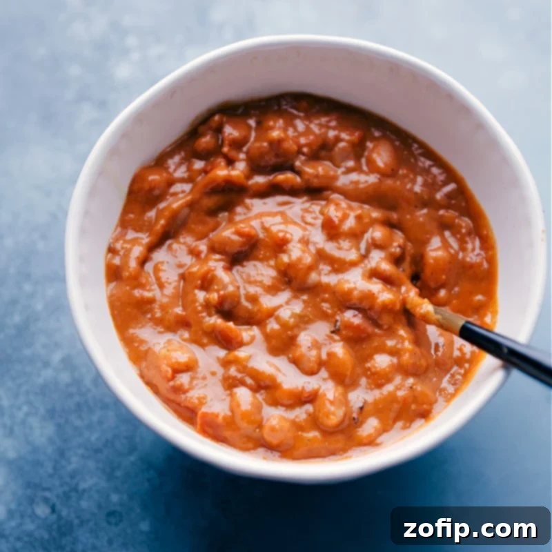 Perfectly cooked, creamy pinto beans – the flavorful foundation for our healthy and satisfying Pinto Bean Tacos. Overhead image of creamy, seasoned pinto beans in a rustic bowl, with a spoon resting in them, ready to be scooped into tacos.