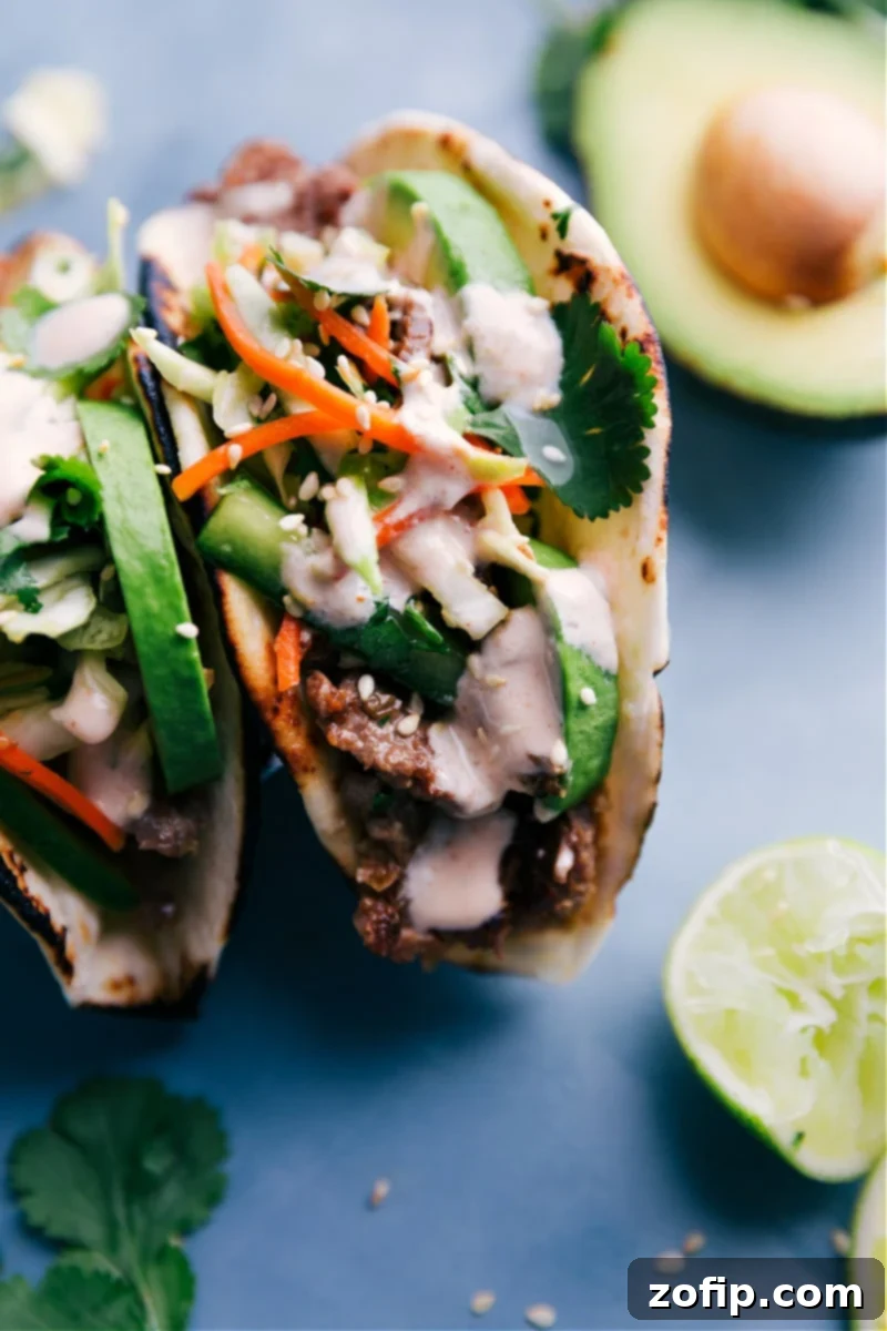 Experience an explosion of flavor with Korean Beef Tacos, featuring tender marinated beef, a quick crunchy slaw, and a delicious Sriracha-lime sauce in charred tortillas. Close-up image of delicious Korean Beef Tacos, showcasing tender marinated beef, fresh crunchy slaw, and a vibrant Sriracha-lime sauce.