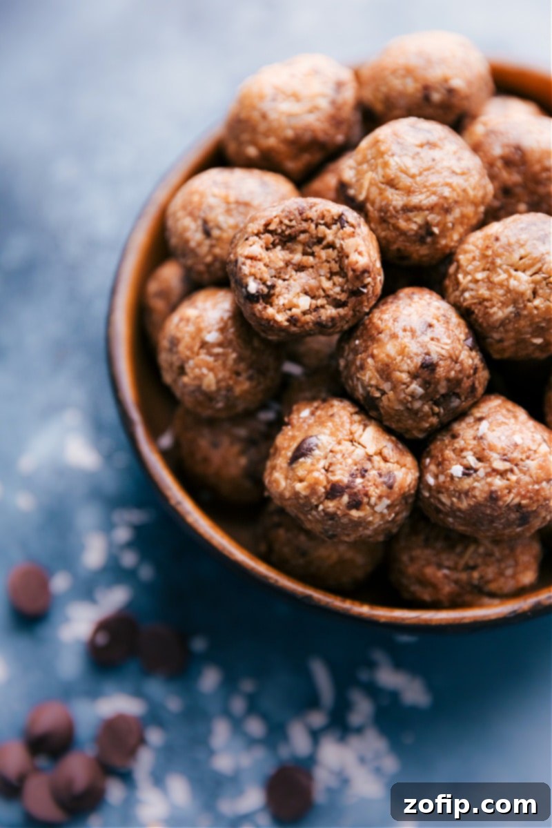 Wholesome Oatmeal Bites 6 A close-up of a bowl filled with Oatmeal Energy Bites, with one bite partially eaten, highlighting its chewy interior and rich chocolate pieces. These are the best Oatmeal Energy Balls, packed with oats, coconut, and chocolate, tasting like healthy oatmeal chocolate chip cookies.