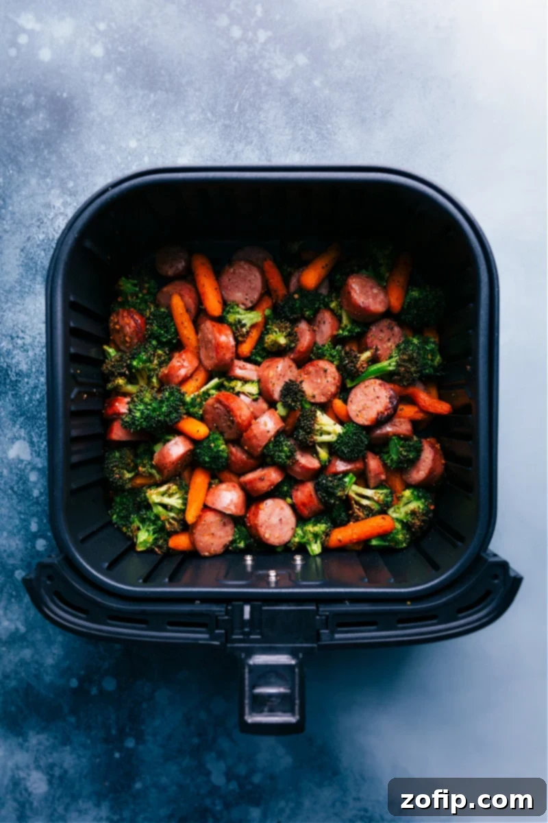 Overhead view of the sausage and veggies in the air fryer basket, perfectly cooked and lightly browned.