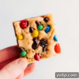 Close-up of a stack of M&M Cookie Bars, showing their chewy texture and colorful candies.