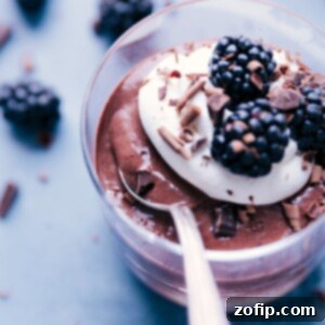 Small jar of Chocolate Chia Seed Pudding topped with berries and whipped cream.