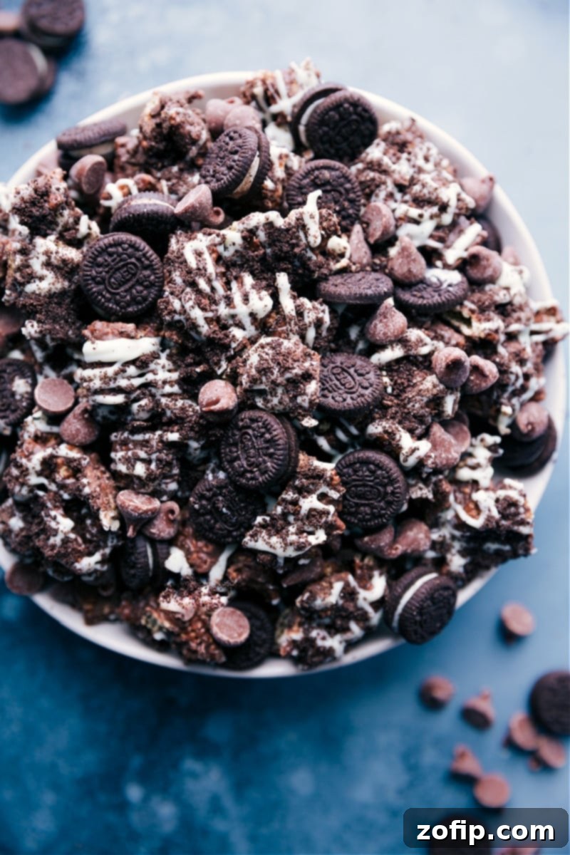Overhead shot of Cookies and Cream Muddy Buddies piled high in a bowl, showcasing the rich chocolate coating, Oreo crumbs, and optional mini Oreos and chocolate chips.