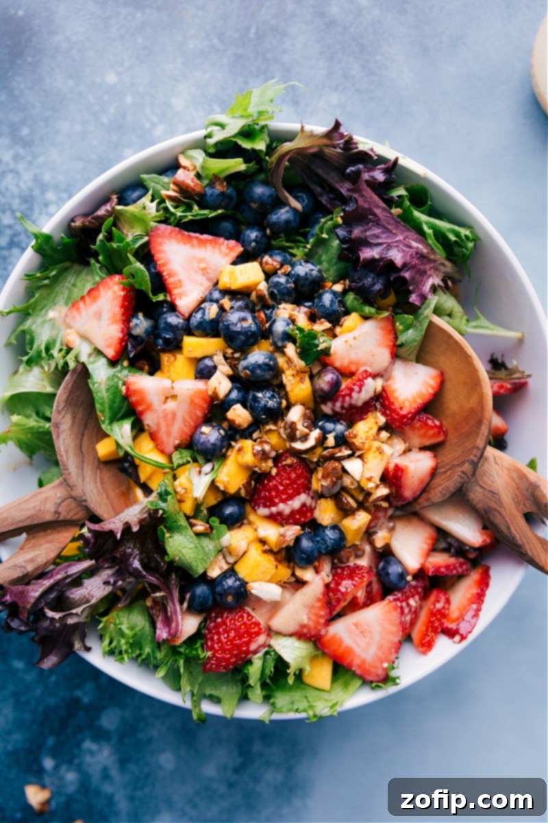 Overhead view of a vibrant Mango Salad featuring blueberries, strawberries, and a luscious dressing.