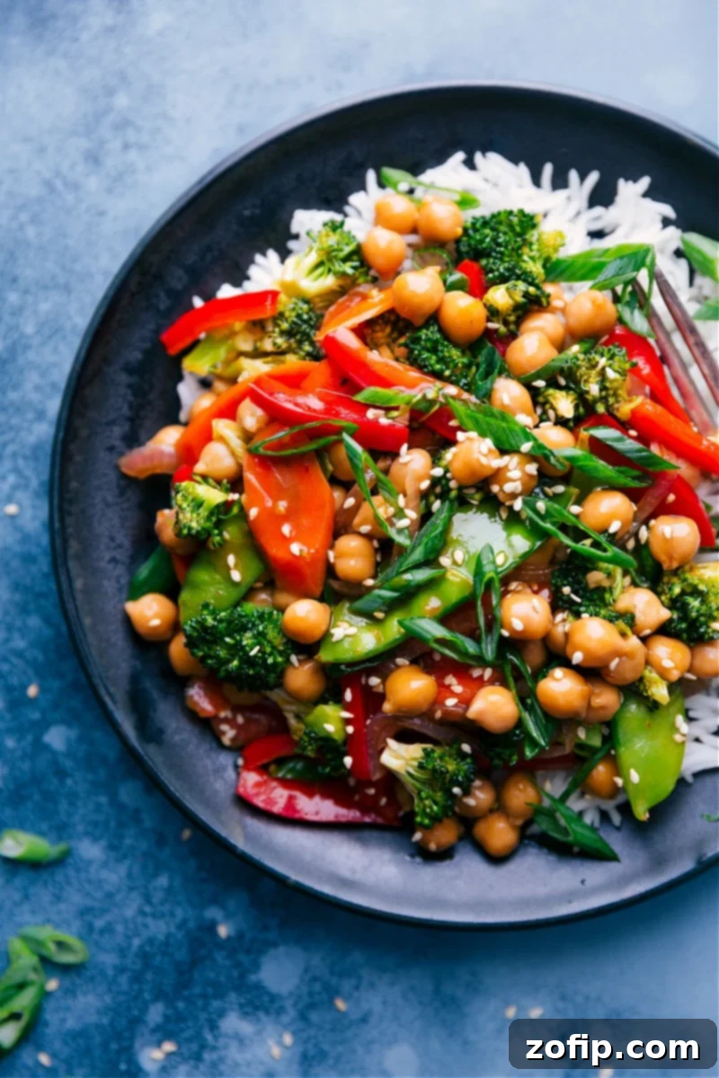 Overhead shot of General Tso Chickpeas served over a bed of white rice, garnished with sesame seeds and green onions.