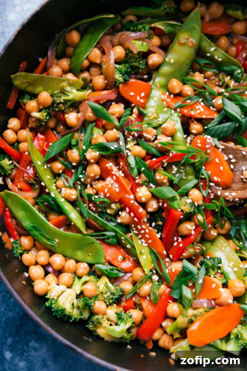 Close-up shot of General Tso Chickpeas simmering in a pan, coated in a glossy, thick sauce.