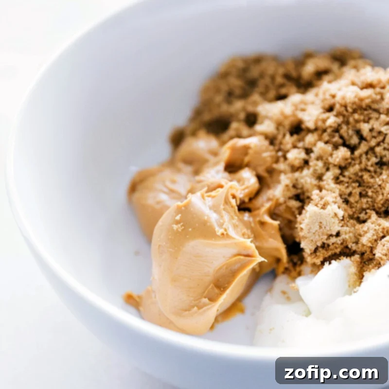 Peanut butter, coconut oil, and sugar in a bowl, perfectly prepped and ready to be mixed for the gluten-free monster cookie dough.