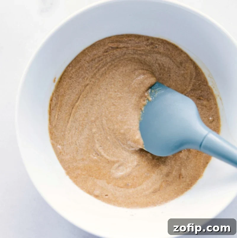 Ingredients for gluten-free monster cookies melted and mixed together in a bowl, showing a creamy, perfectly combined dough ready for the next steps.