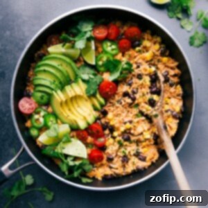 Mexican chicken and rice in the skillet, topped with fresh vegetables ready to be mixed in, and all set to be enjoyed.