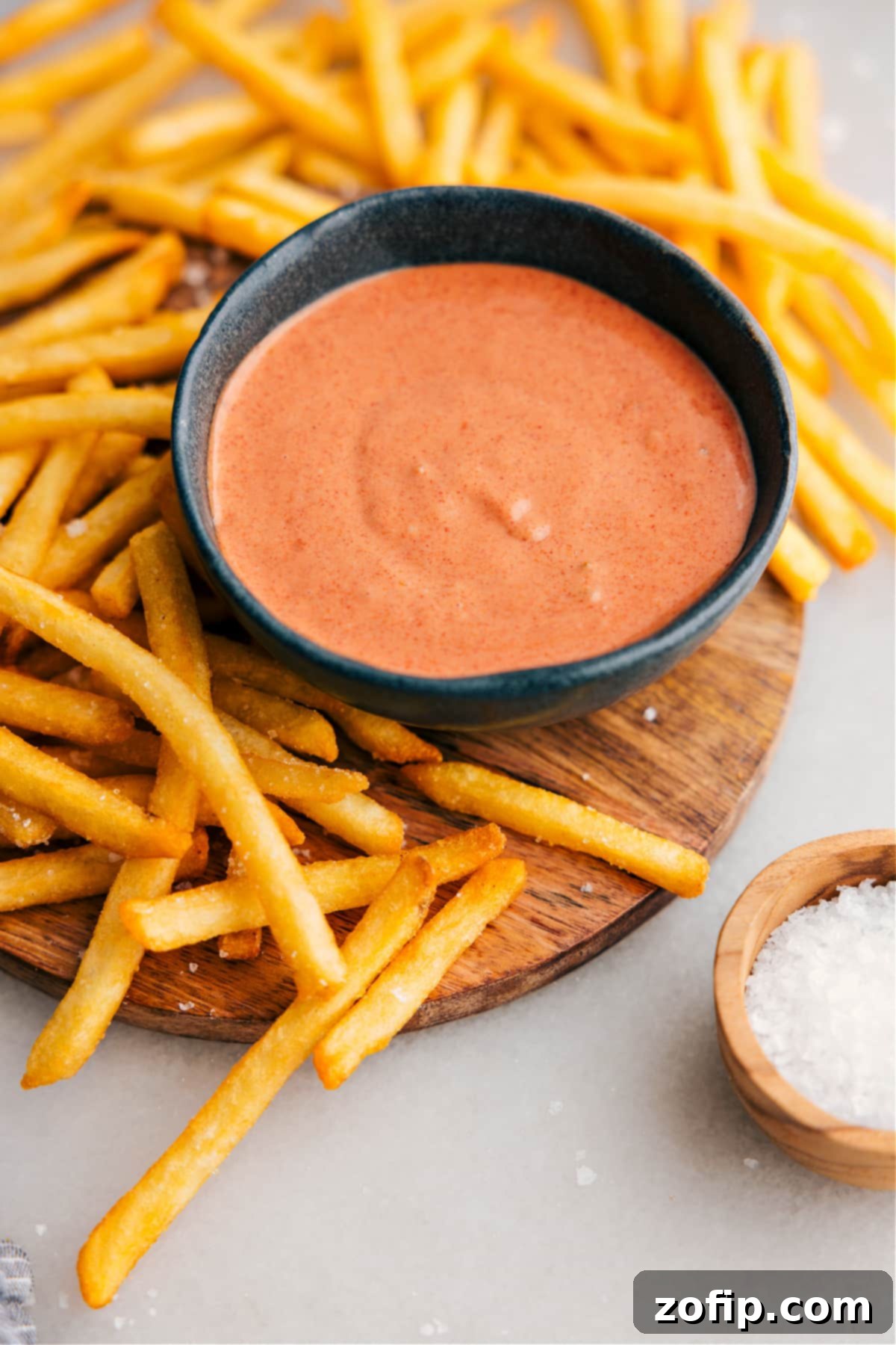 Dipping Your Fries In Fry Sauce A delectable serving of homemade fry sauce in a stylish bowl, accompanied by a side of crispy golden fries, ready for dipping.