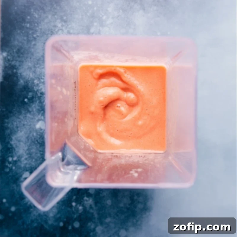 An inviting overhead view of a vibrant Caribbean Passion Smoothie swirling in a blender, perfectly blended and ready to pour.