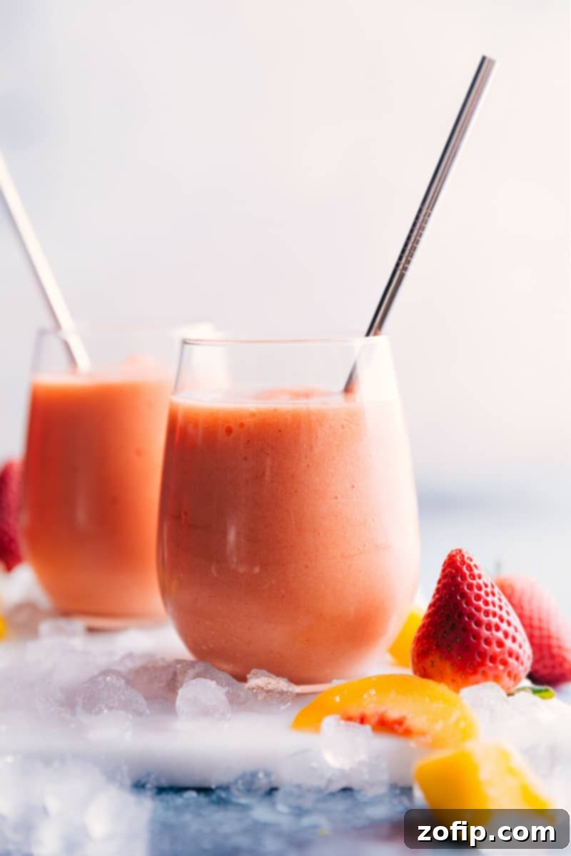 Two tall glasses filled with Caribbean Passion Smoothies, garnished with fresh fruit, against a bright, sunny background.