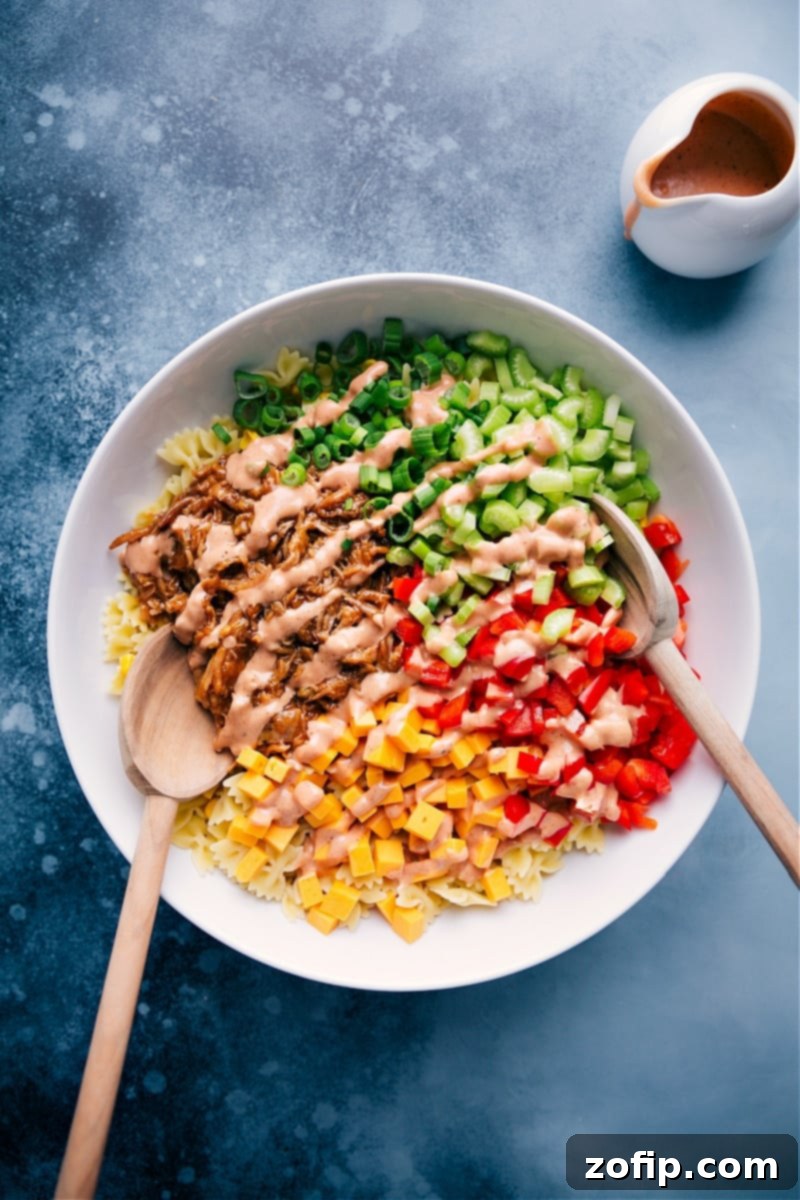 Large bowl of BBQ Pasta Salad drizzled with creamy dressing, garnished with fresh herbs, ready to serve at a summer gathering.