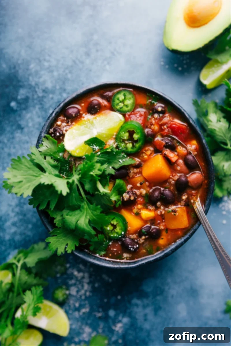 A vibrant overhead shot of Butternut Squash Chili in a bowl, garnished with fresh cilantro and a dollop of sour cream, showcasing its rich texture and colorful ingredients.