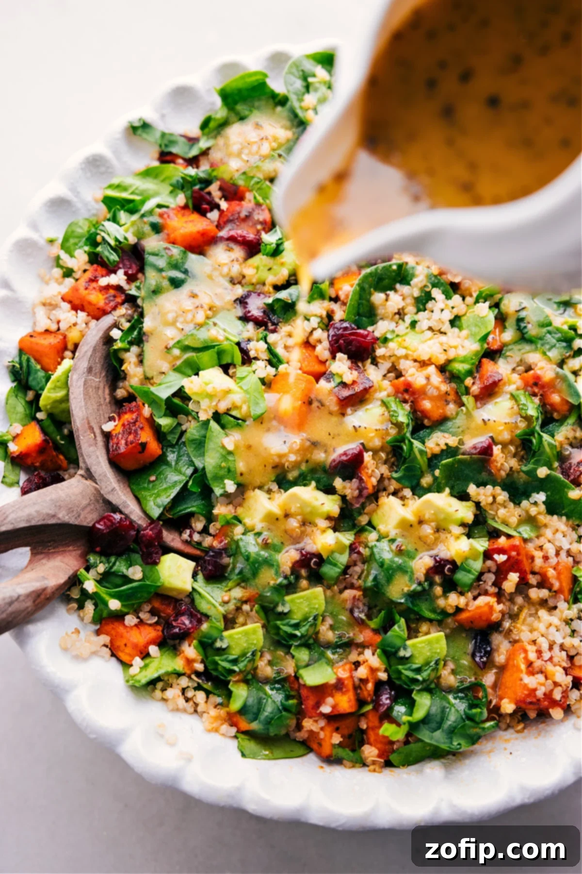 The tangy lemon dressing being drizzled generously over the vibrant Sweet Potato Quinoa Salad, bringing all the flavors together in a harmonious blend.