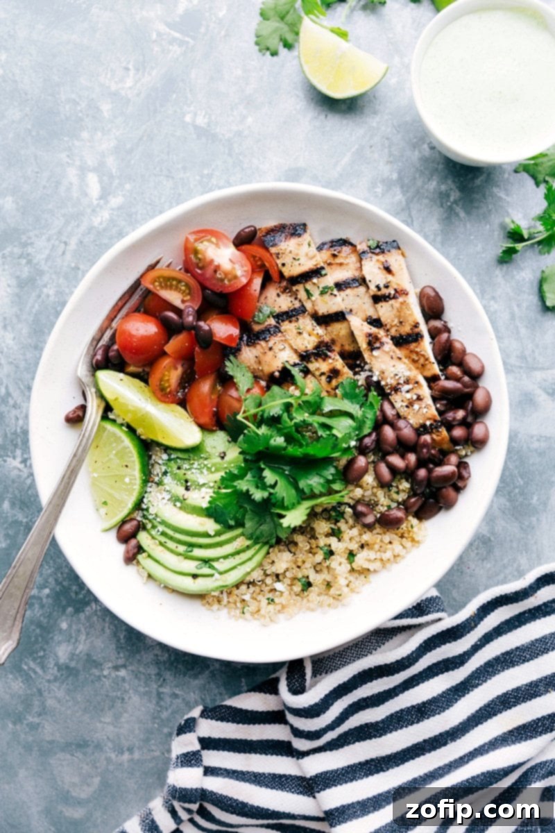 A bowl filled with honey-lime chicken served with quinoa, tomatoes, avocados, and black beans, creating a flavorful and wholesome meal.