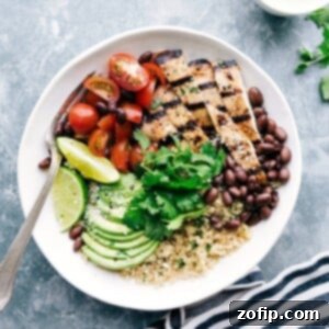 A bowl filled with honey-lime chicken served with quinoa, tomatoes, avocados, and black beans, creating a flavorful and wholesome meal.