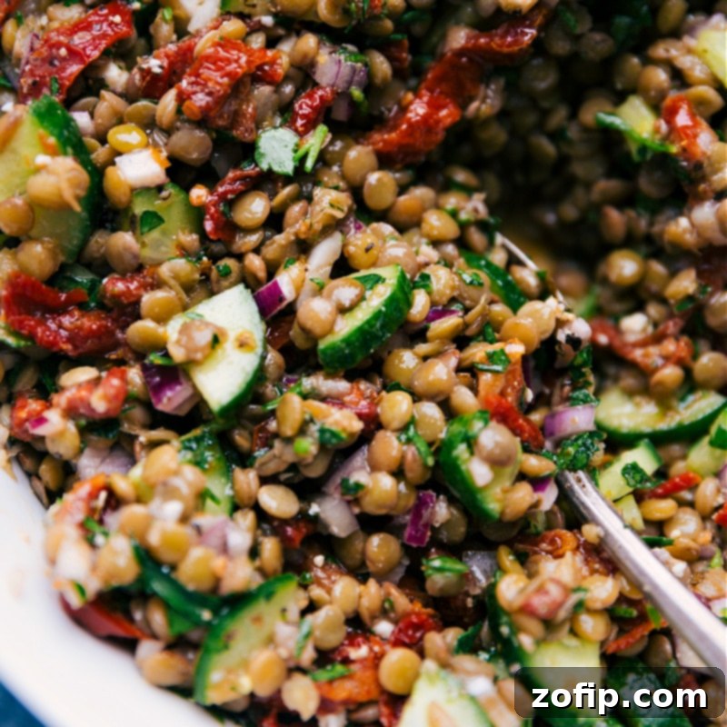 A large, inviting white bowl filled with freshly prepared Lentil Salad, vividly showcasing its vibrant colors and appealing textures, beautifully plated and ready to be served and enjoyed as a healthy and satisfying meal.