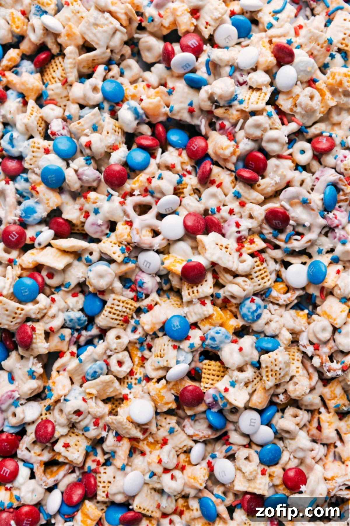 Delicious 4th of July Snack Mix A vibrant bowl of 4th of July Snack Mix, featuring red, white, and blue candies, pretzels, and various cereals coated in white chocolate, ready to be enjoyed at a festive gathering.