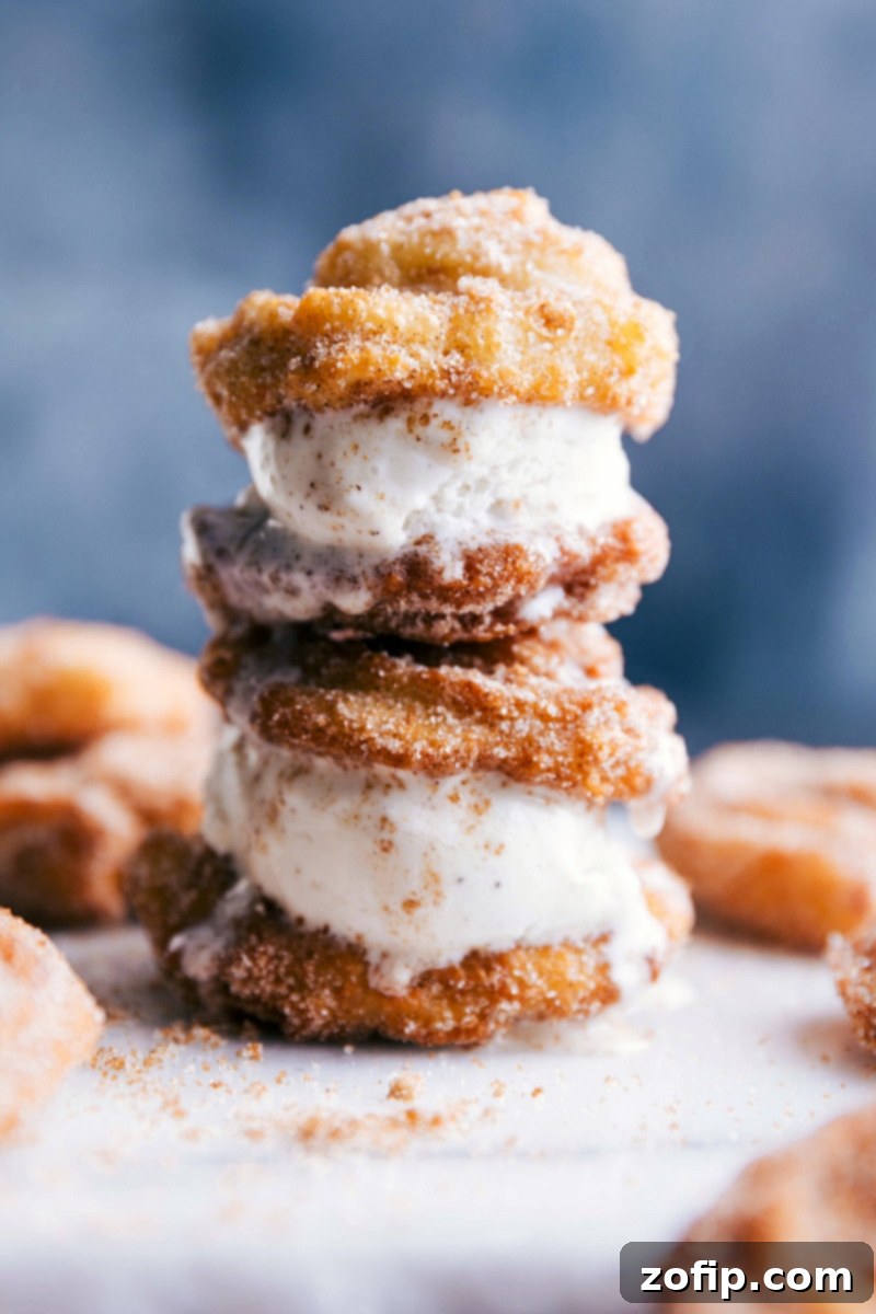 Two churro ice cream sandwiches stacked high, with creamy ice cream generously oozing out the sides, ready for enjoyment.
