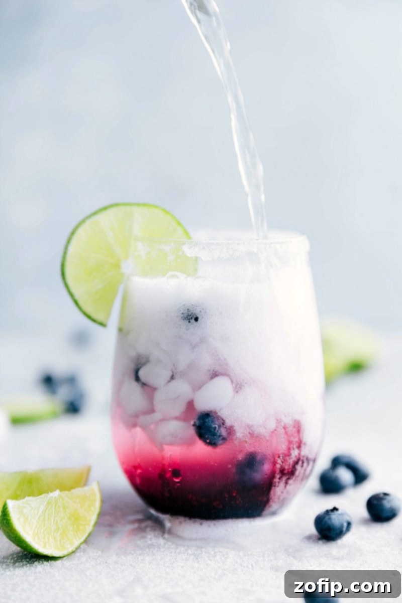 A pitcher of homemade blueberry syrup, essential for crafting the delicious blueberry-lime spritzer. The syrup base provides a natural sweetness and rich berry flavor.