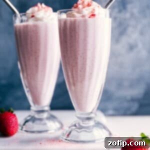 Two strawberry milkshakes with whipped cream on top and straws in them, a thick and delicious dessert.