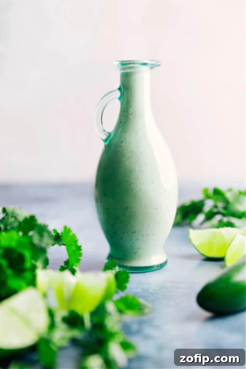 A glass jar filled with luscious Cafe Rio Salad Dressing, garnished with fresh cilantro sprigs and lime slices, set against a rustic background, ready to be drizzled over your favorite dishes.