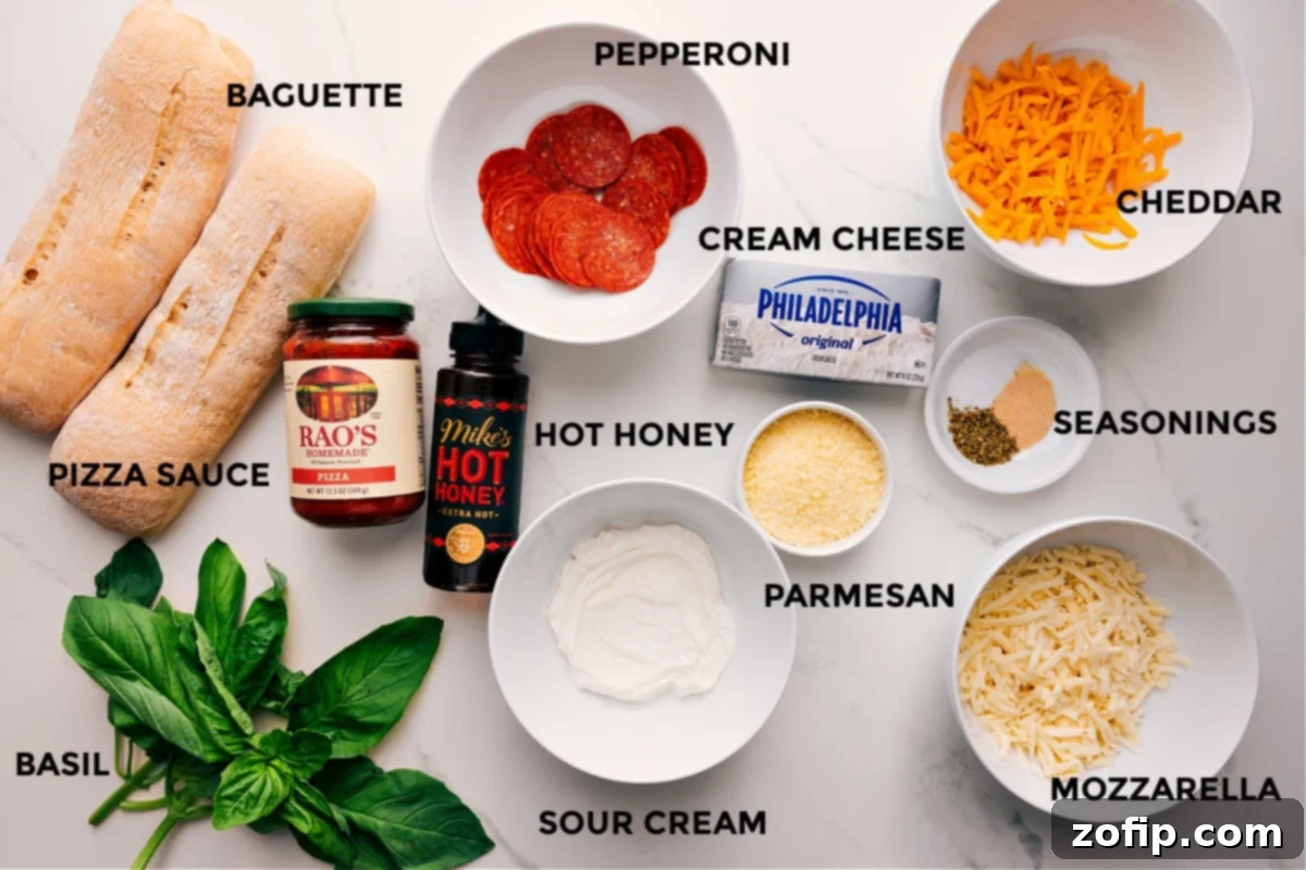 Ingredients In Pizza Dip Recipe All the ingredients in this recipe prepped out for easy assembly including the baguette, basil, pizza sauce, hot honey, sour cream, pepperoni, cream cheese, parmesan, mozzarella, seasonings, and cheddar.