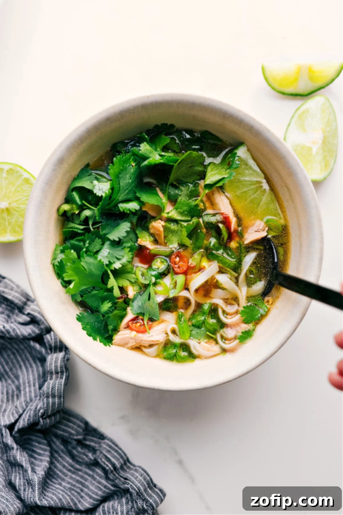 Chicken Pho Delight 2 Chicken Pho Recipe in a bowl with fresh cilantro, lime, and peppers on top.