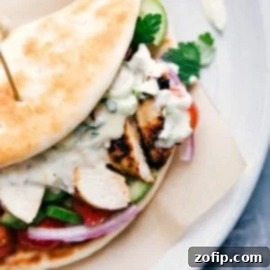 A complete chicken gyro, overflowing with chicken, vegetables, and sauce, wrapped in a soft pita