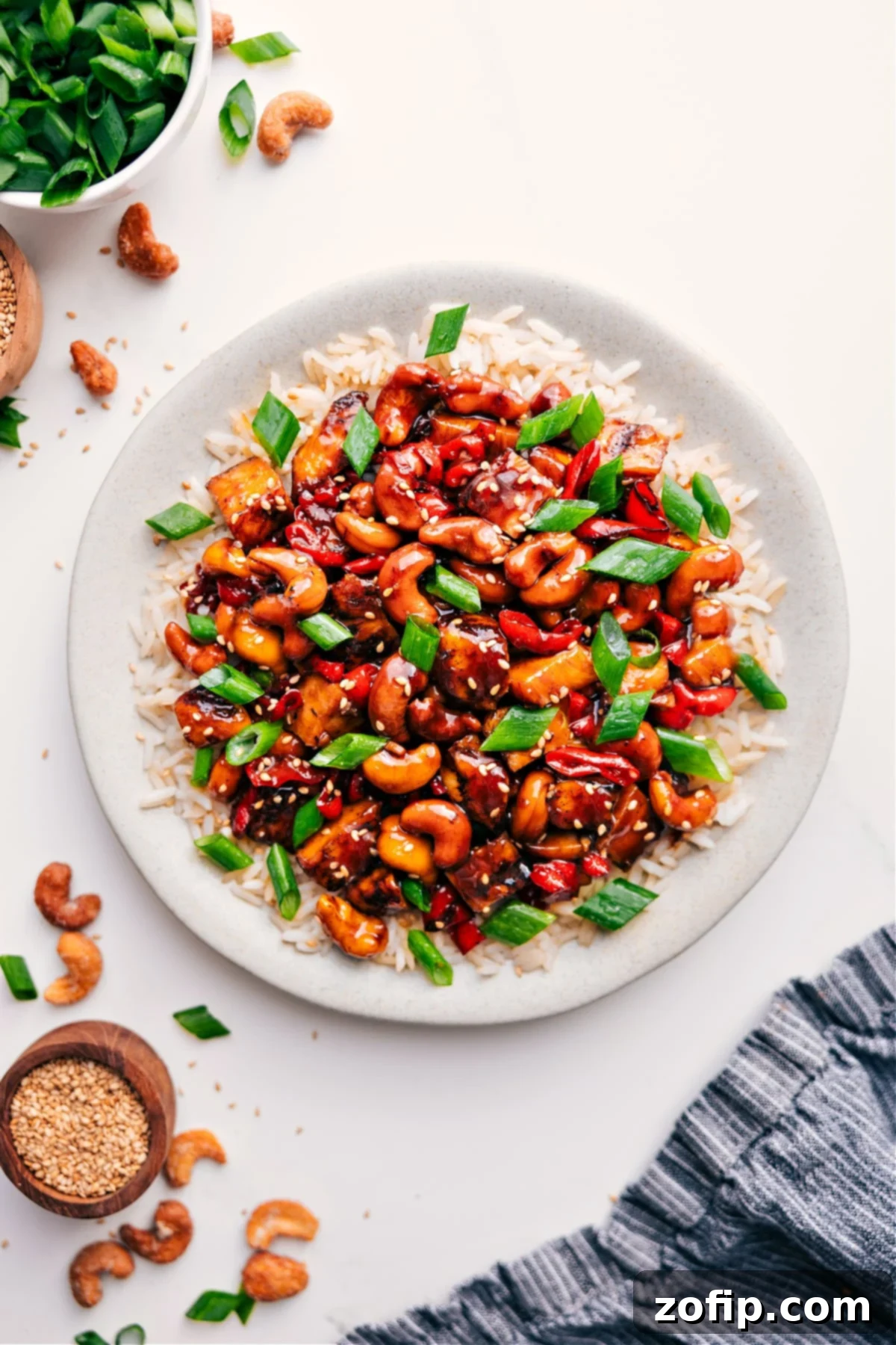 Super Simple and Delicious Cashew Chicken Recipe Cashew Chicken served over rice with green onions and sesame seeds.