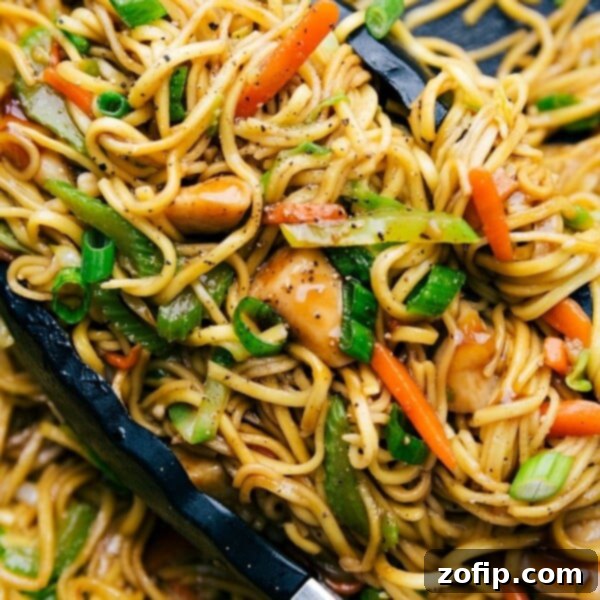 Cashew Chicken Delight 3 Chicken chow mein in a skillet with tongs, filled with fresh vegetables, perfectly cooked and seasoned.